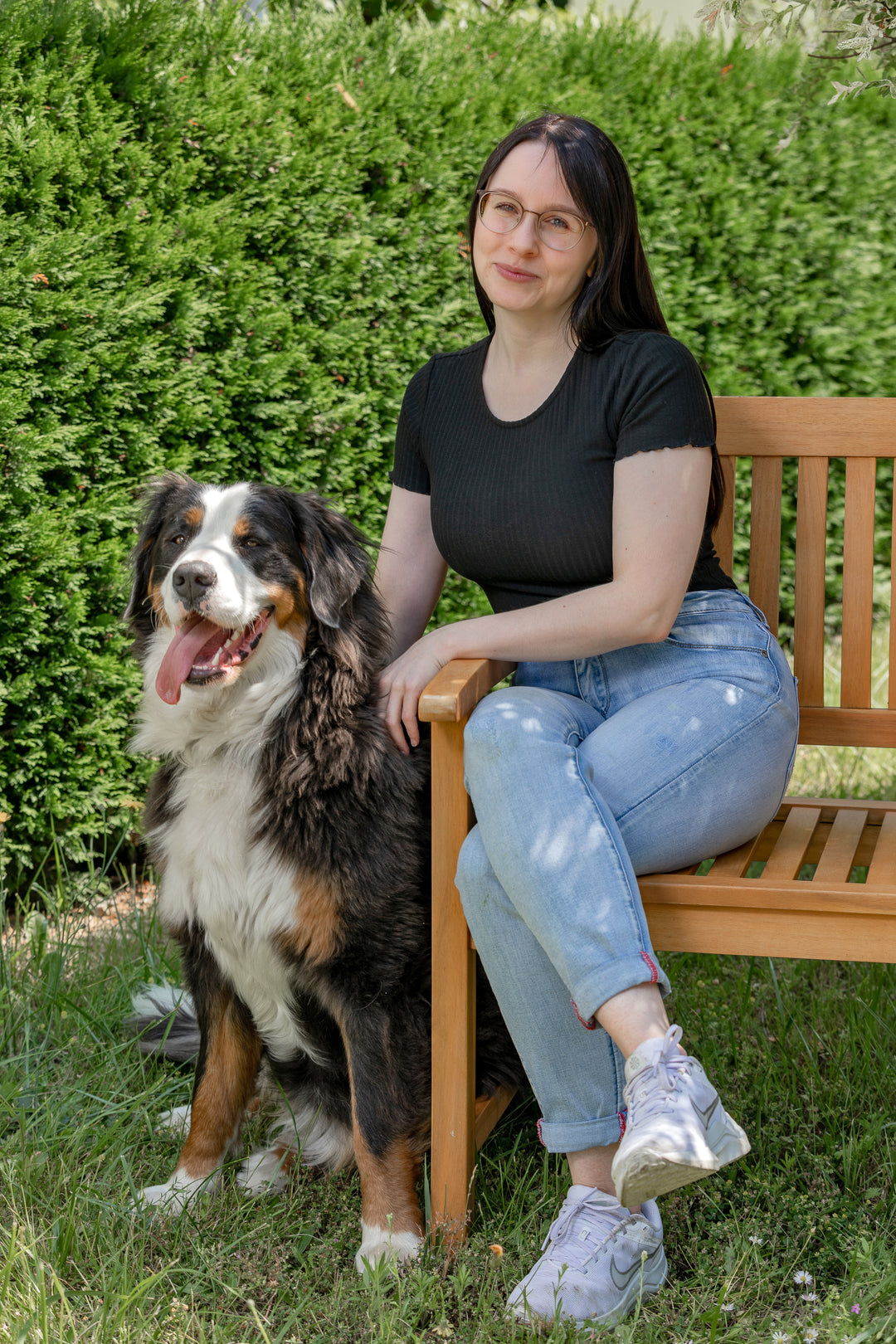 Shopinhaberin von Balau Naturkosmetik mit ihrer Berner Sennenhündin Luna auf einer Holzbank im Garten